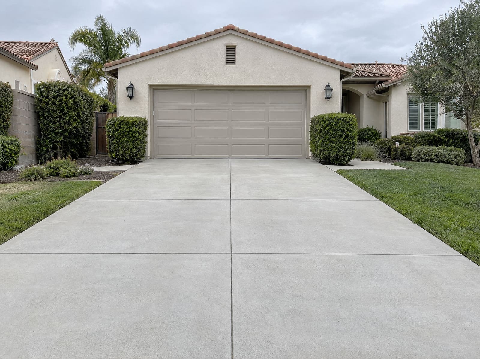 The same driveway after pressure washing: the concrete an even pale grey, the oil stain and mildew gone, the edges crisp.
