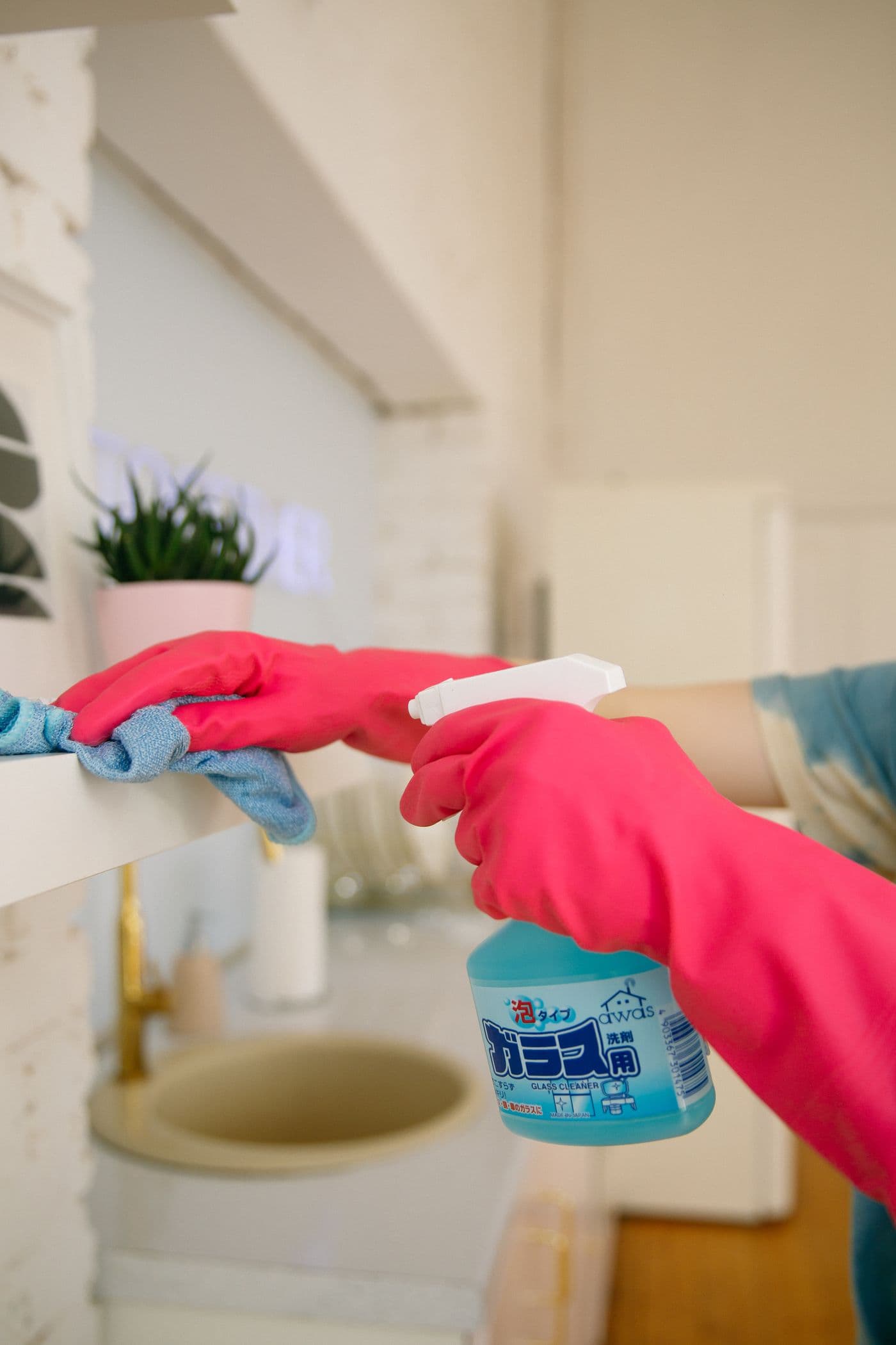 Spray bottle and cloth being used to detail a kitchen shelf